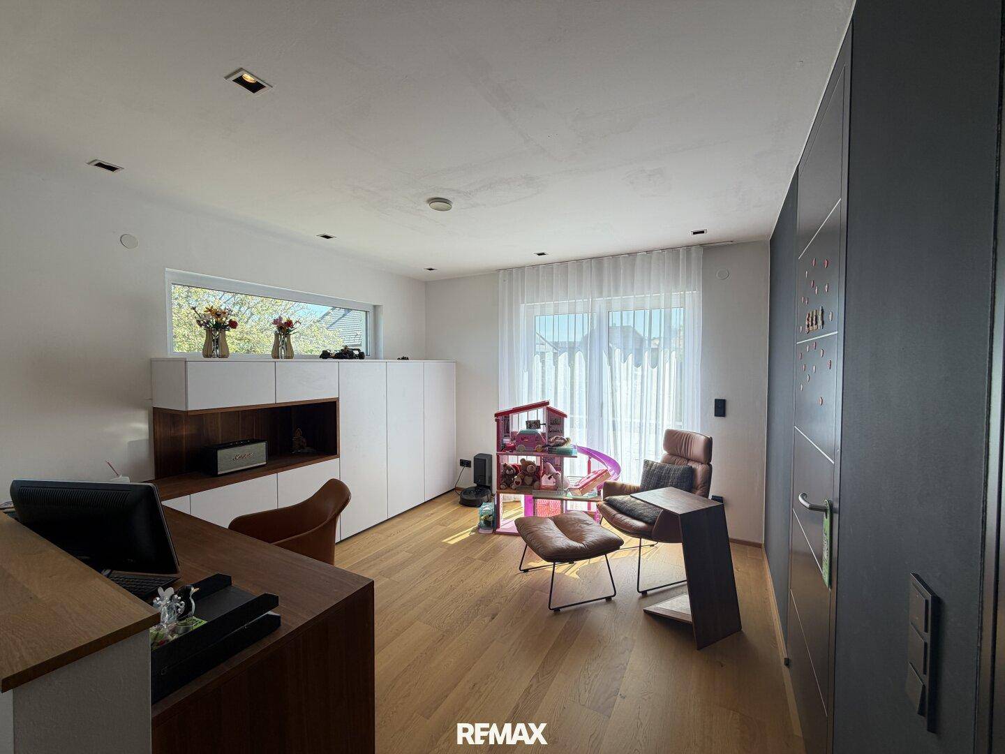 Helles Arbeitszimmer mit Holzboden, modernen Möbeln und großem Fenster für Tageslicht.