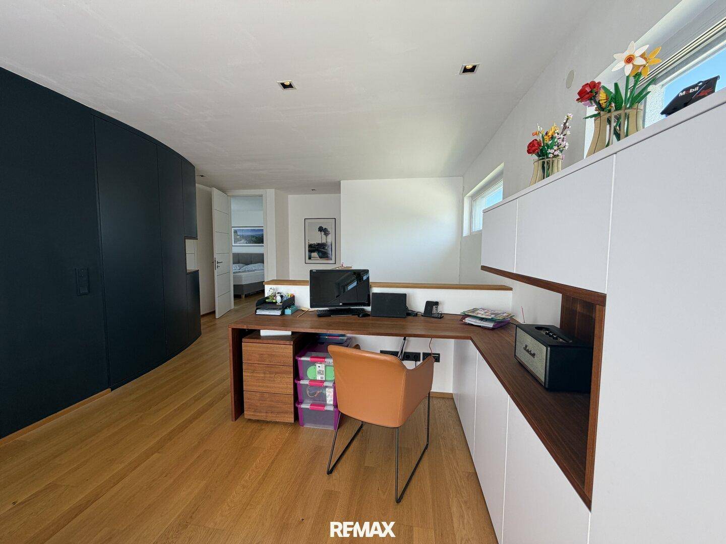 Funktionales Arbeitszimmer mit Holzboden, integriertem Schreibtisch und Blick auf den Flur.