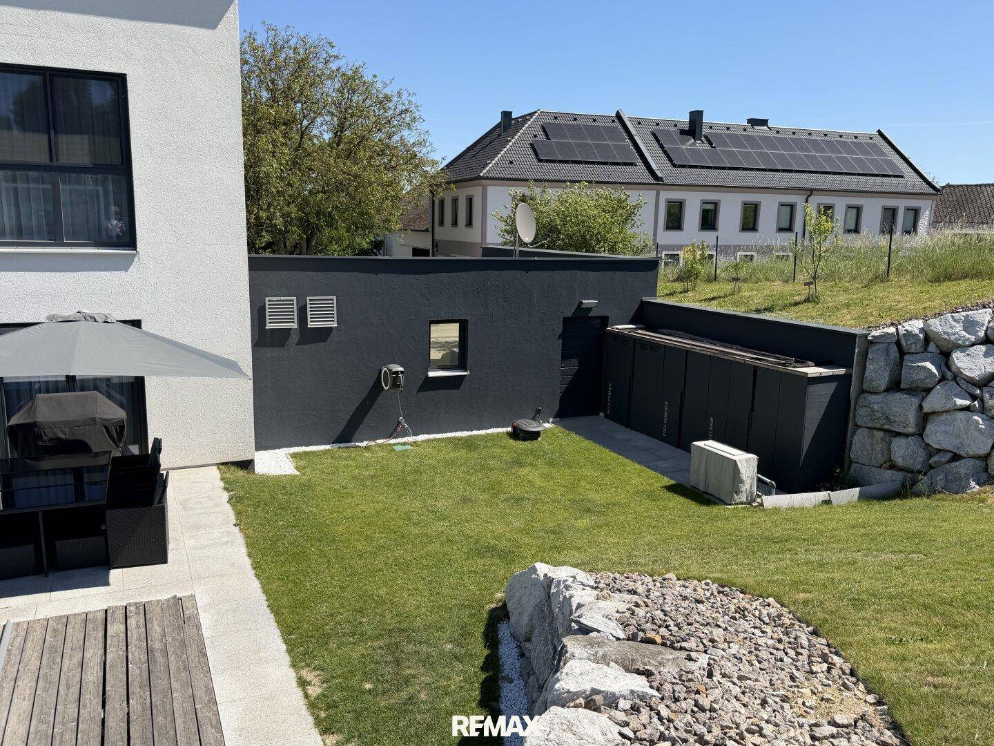 Gepflegter Gartenbereich hinter dem Haus mit Rasenfläche und angrenzendem Nebengebäude.