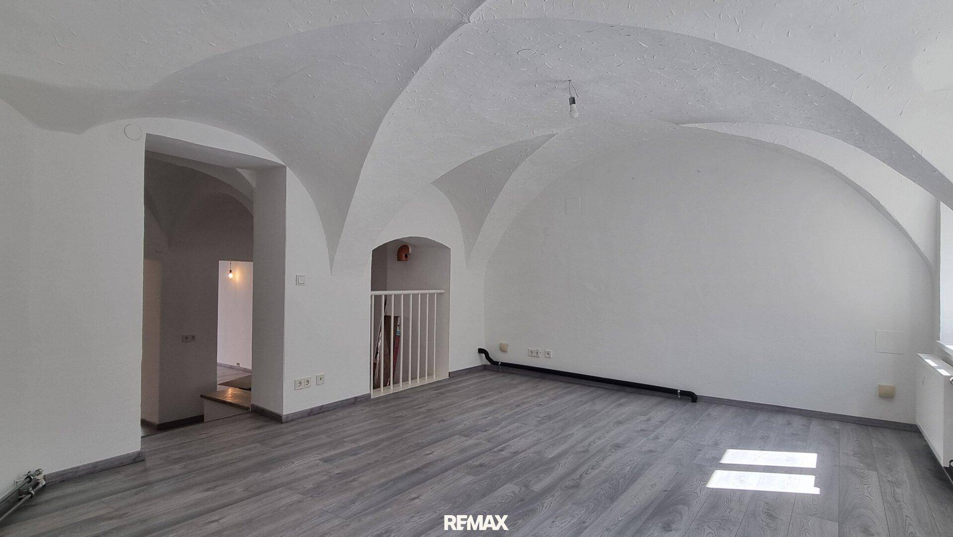 Heller Raum mit beeindruckender Gewölbedecke und modernem Laminatboden, bereit zur Gestaltung.
