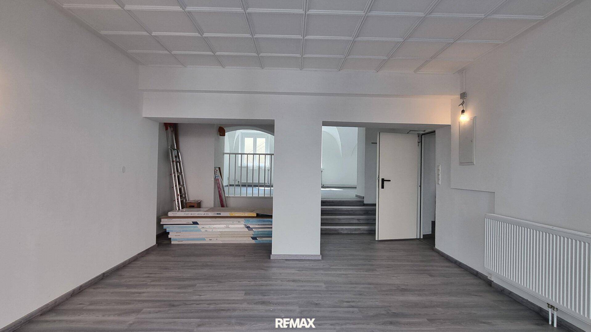 Geräumiger, leerer Innenraum mit Laminatboden und Zugang zu einem Treppenhaus.