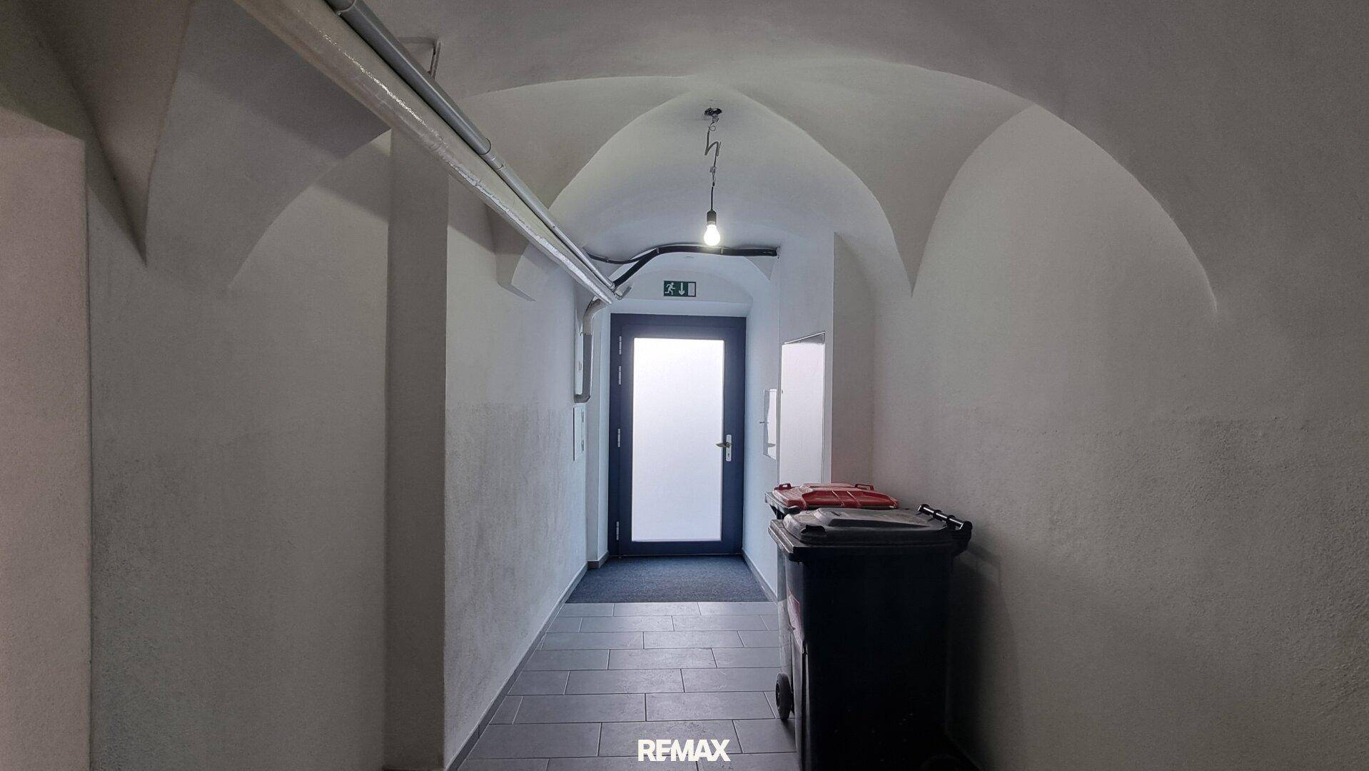 Langer Flur im Untergeschoss mit Gewölbedecke und dunklem Fliesenboden, führt zum Ausgang.