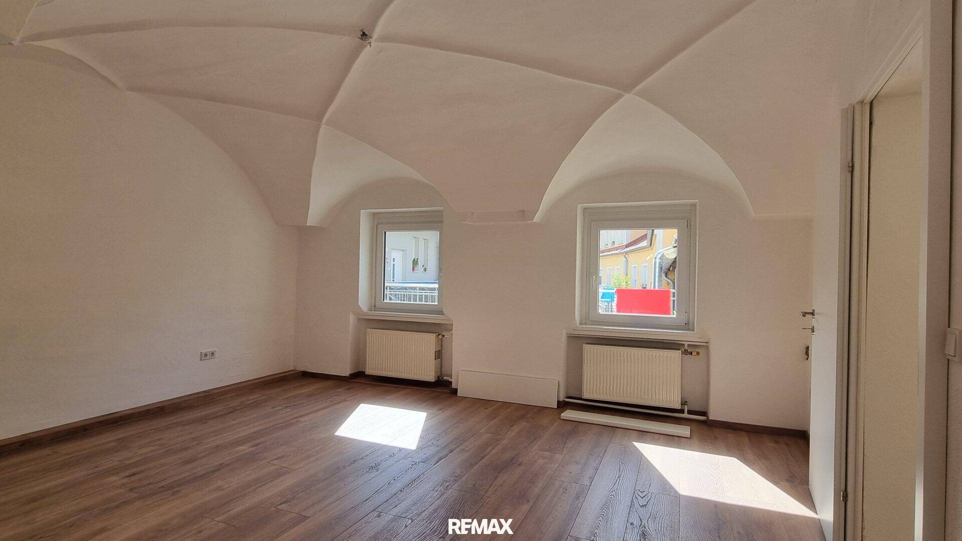 Helles Schlafzimmer mit Gewölbedecke und Holzboden, bietet eine gemütliche Atmosphäre.