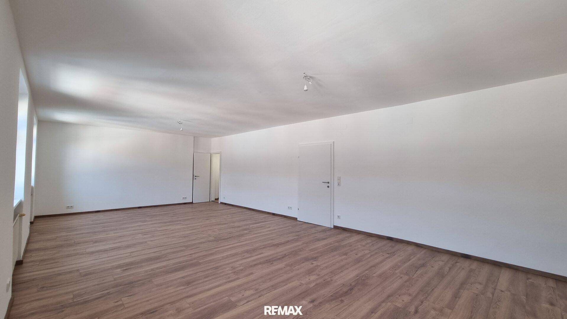 Geräumiges, helles Zimmer mit Laminatboden und weißen Wänden, ideal für flexible Nutzung.