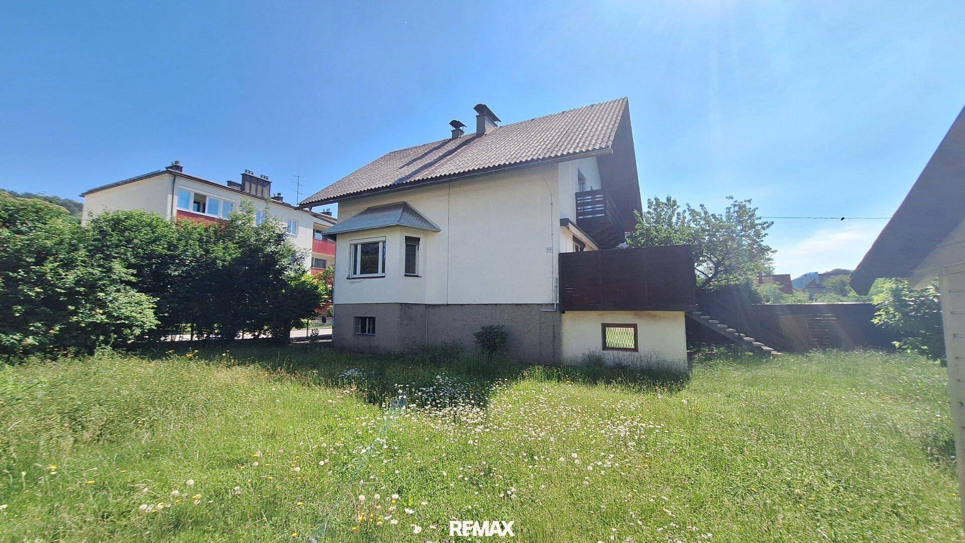 Seitenansicht des Hauses mit großzügiger Rasenfläche im Vordergrund.