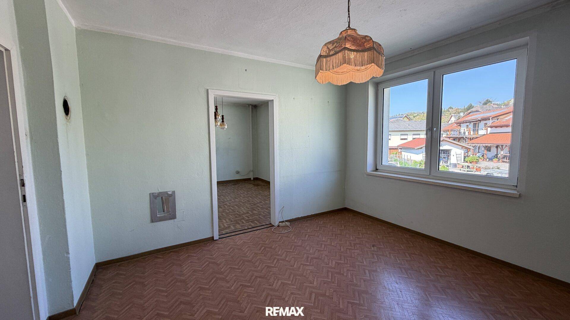 Helles Zimmer mit Laminatboden und großem Fenster, ideal als Schlafzimmer.