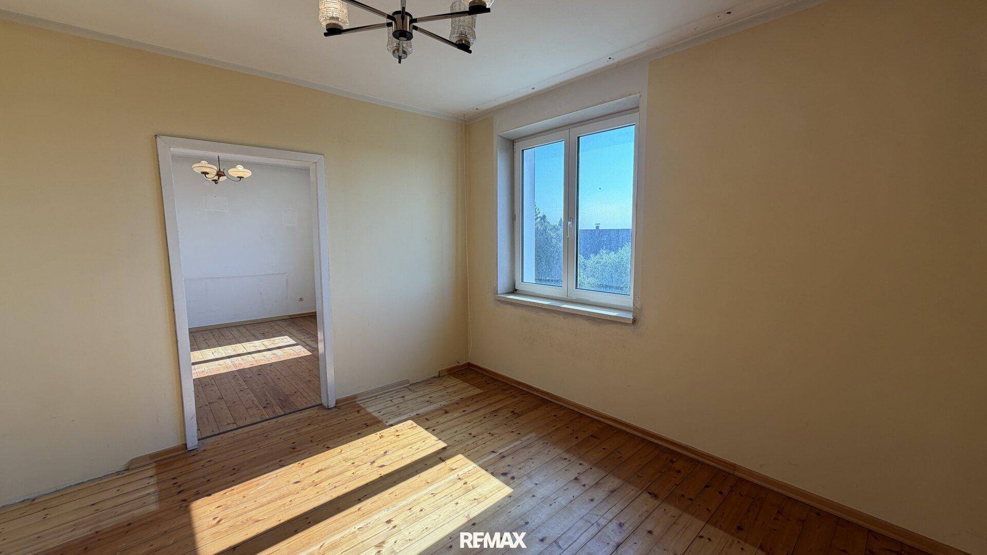 Helles Zimmer mit Holzdielenboden und Fenster, ideal als Kinderzimmer.