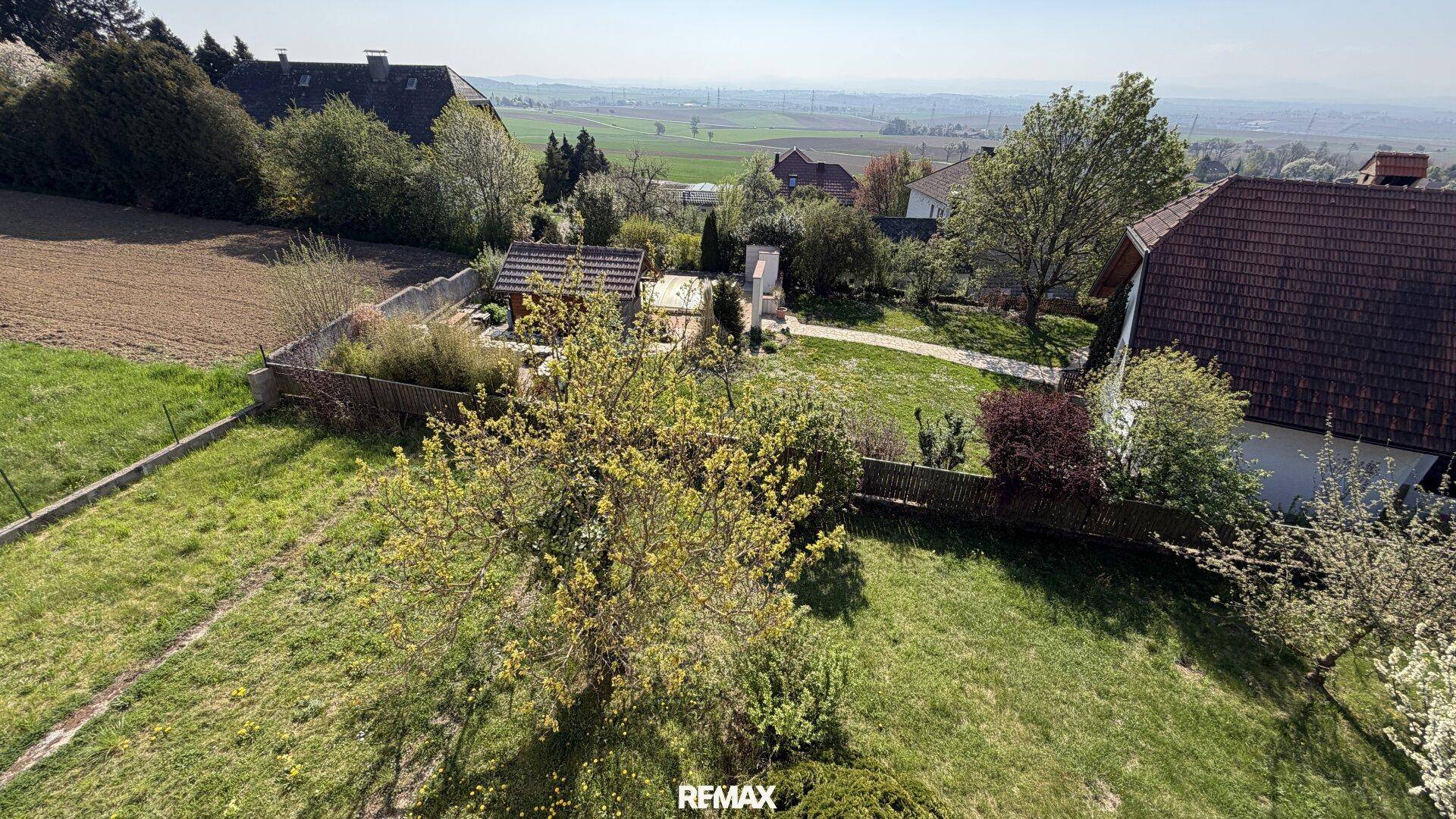 Weitläufiger Gartenbereich mit Rasenfläche, Bäumen und ländlichem Ausblick.