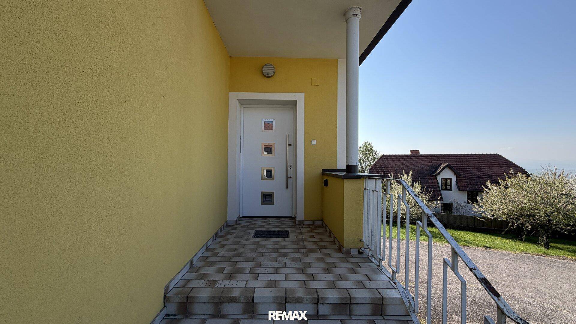 Überdachter Eingangsbereich mit Fliesenboden und Blick auf die Umgebung.