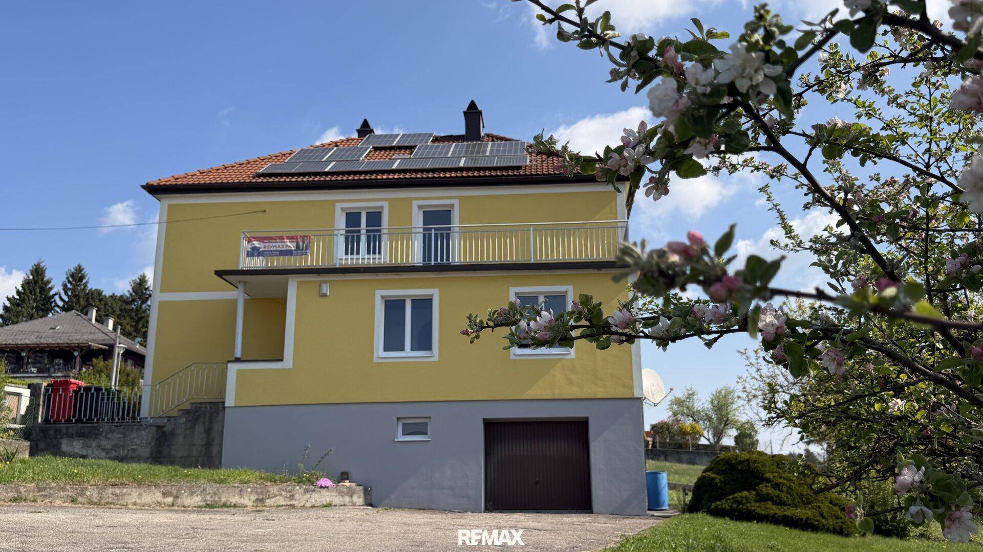 Ansicht des Hauses mit Solaranlage, Balkon und Garage im Untergeschoss.