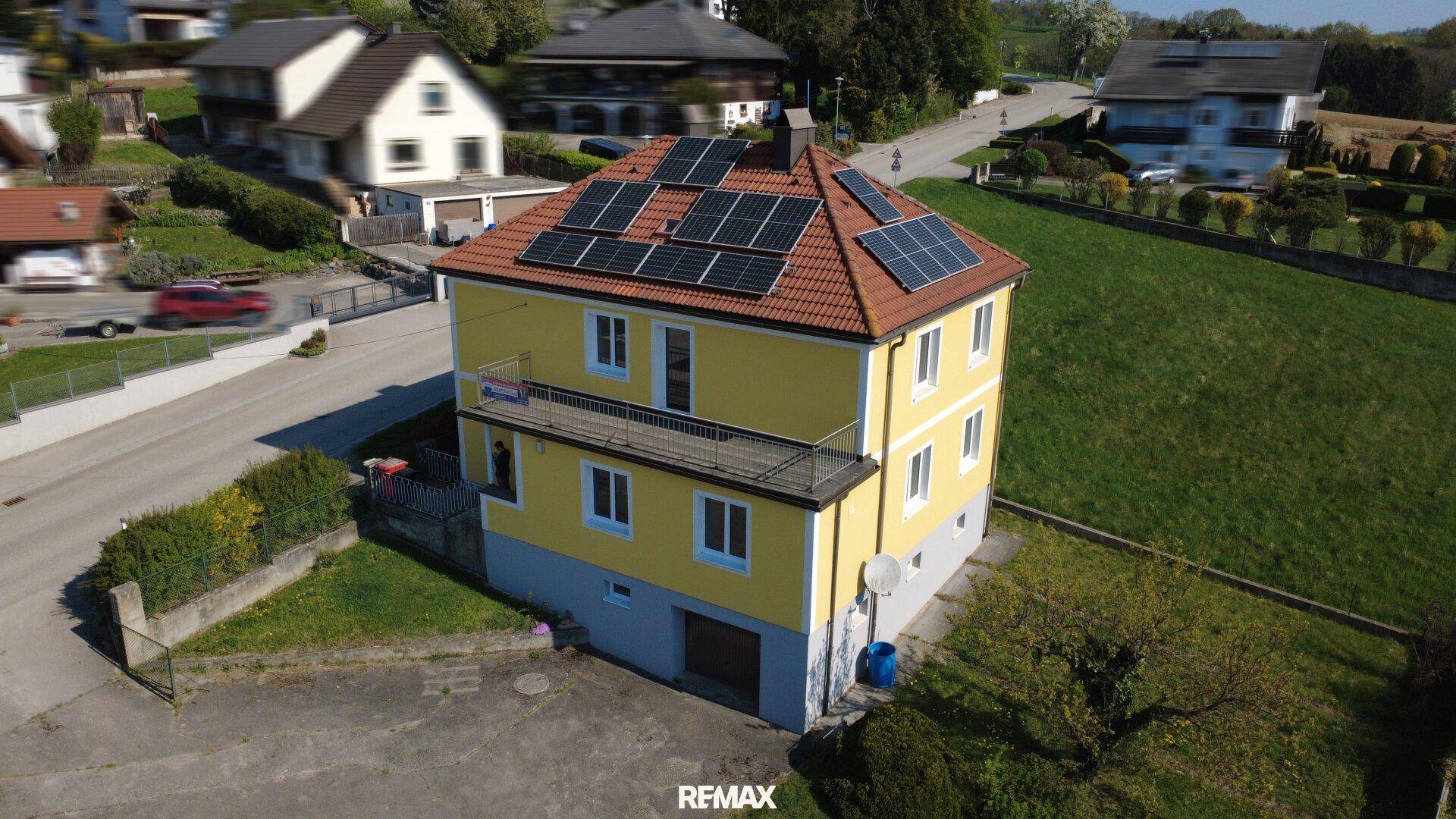 Luftaufnahme des Hauses mit Solaranlage auf dem Dach und umliegender Landschaft.