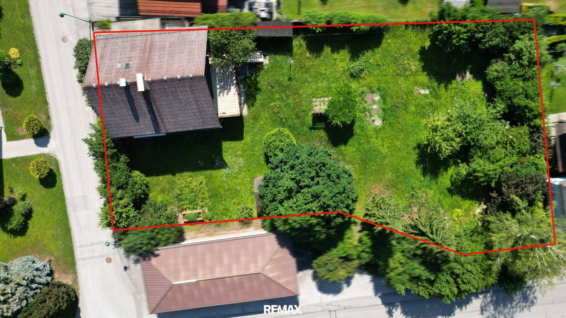 Luftaufnahme des Grundstücks mit Haus und Garten, umrandet von einer roten Linie.