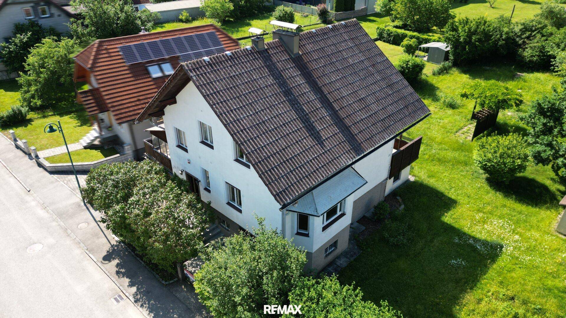 Luftaufnahme des Hauses mit Satteldach, umgeben von viel Grün und einer ruhigen Straße.