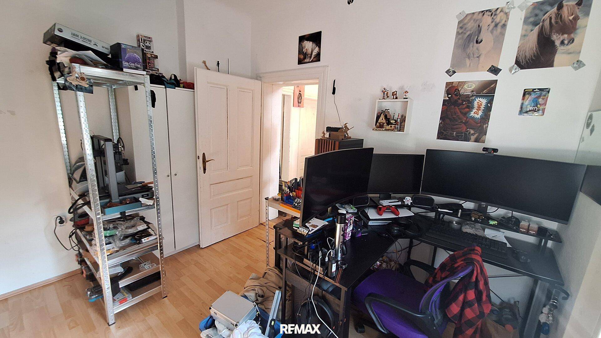 Arbeitszimmer mit mehreren Monitoren, Gaming-Setup und Regalen für Technik.