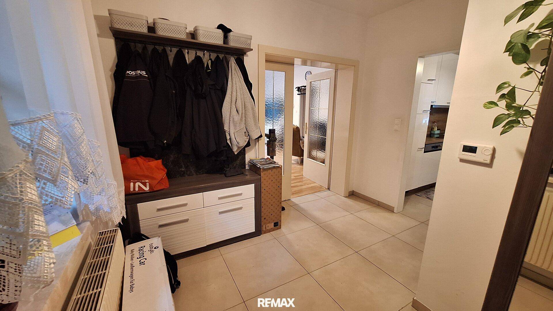 Heller Flur mit Garderobe, Fliesenboden und Zugang zu weiteren Räumen.