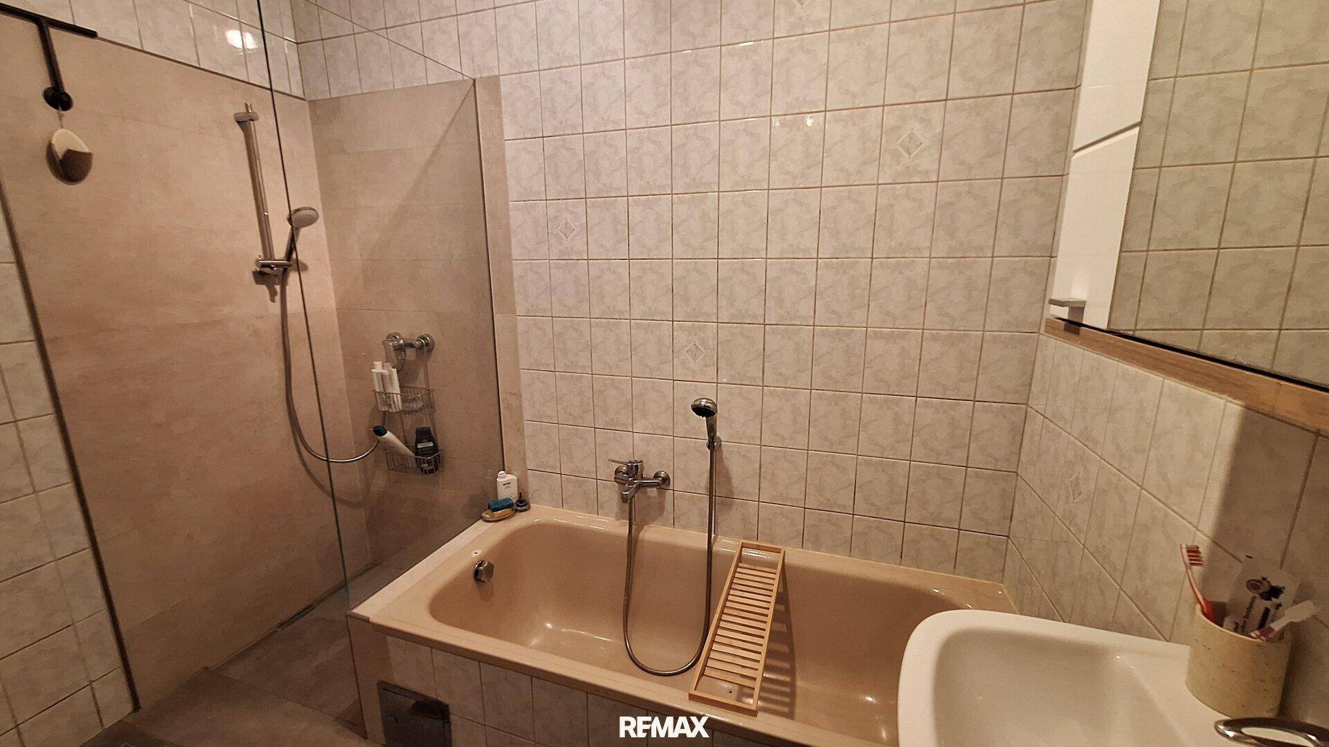 Gefliestes Badezimmer mit Badewanne, Dusche und Waschbecken.