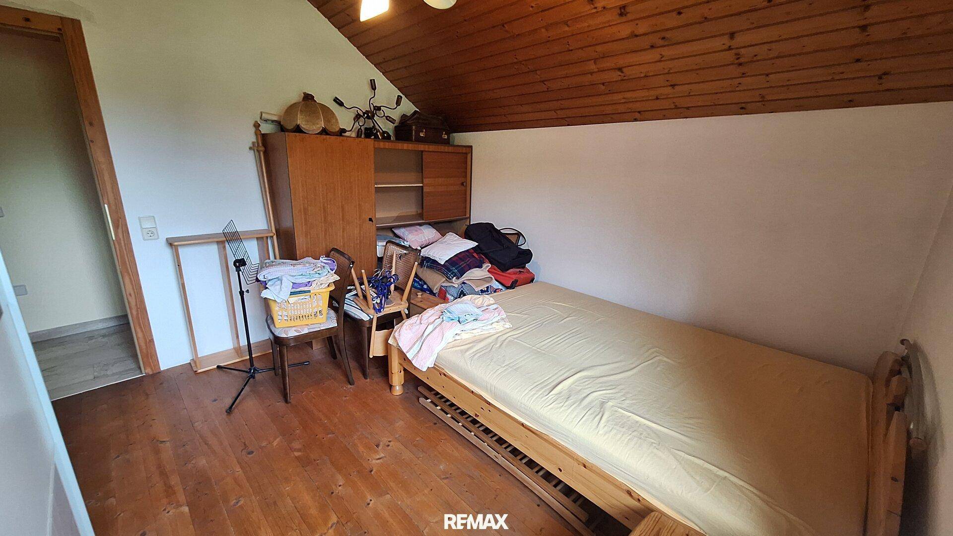 Schlafzimmer im Dachgeschoss mit Holzboden, Holzwänden und Einzelbett.