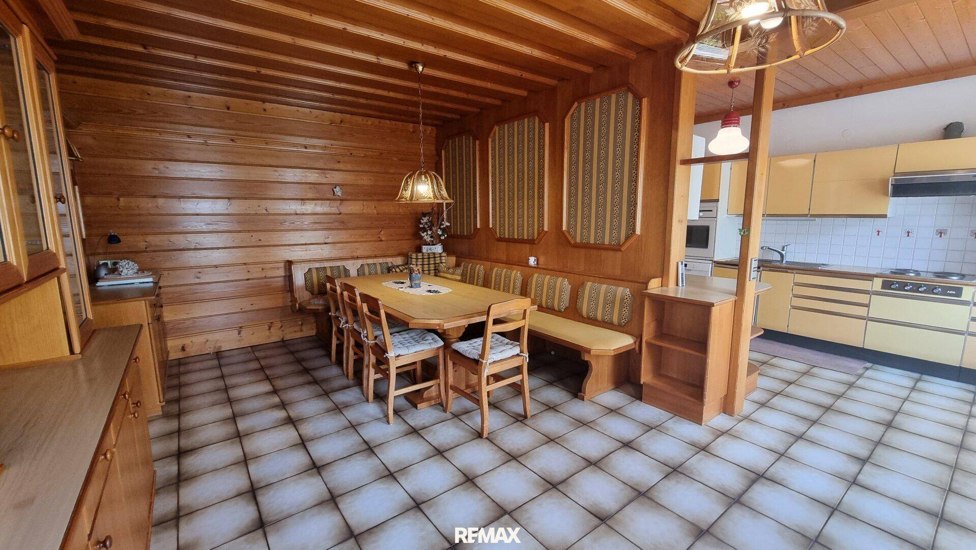 Rustikaler Essbereich mit Holztisch, Eckbank und angrenzender Küche im Landhausstil.
