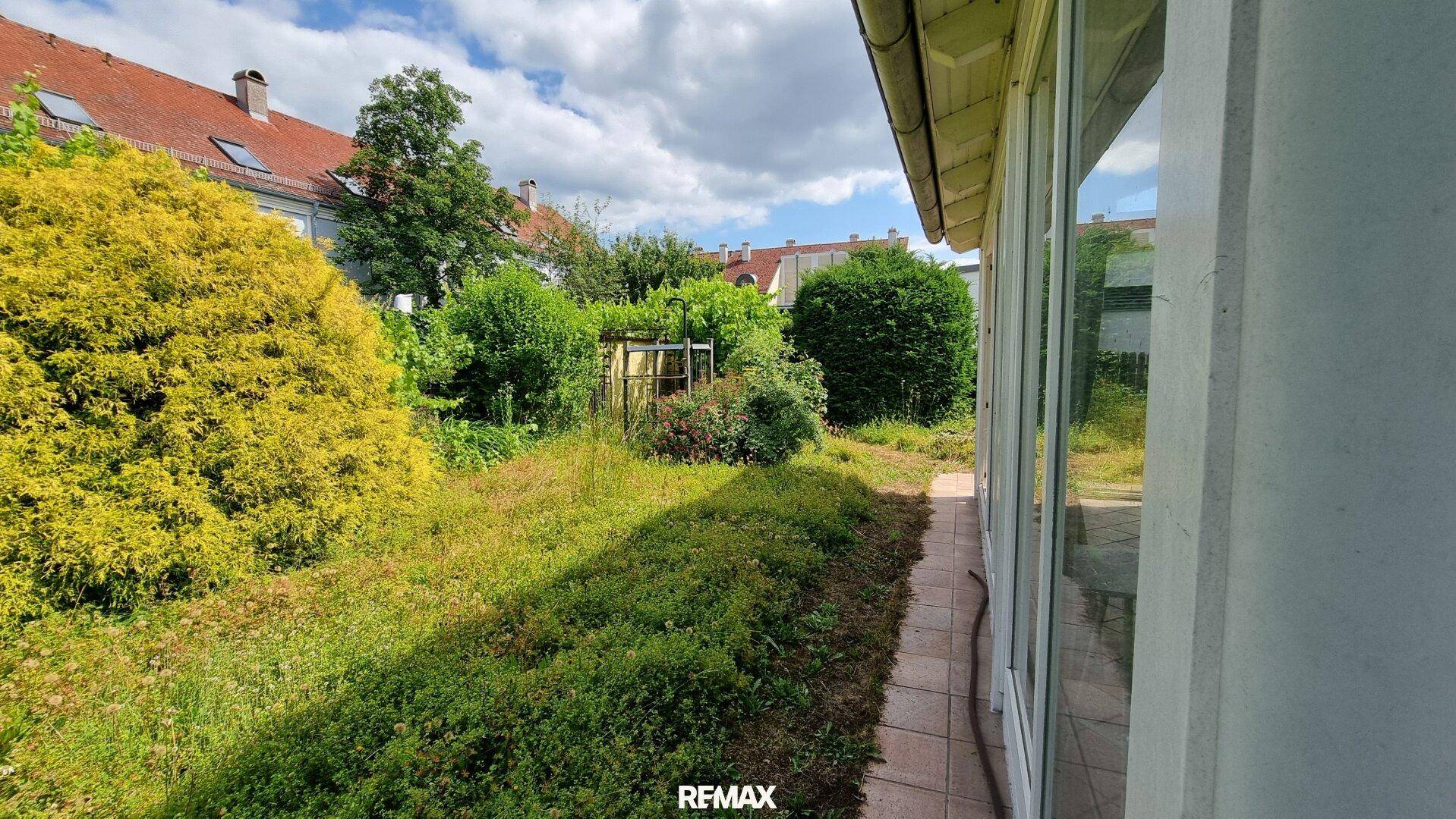 Naturbelassener Gartenbereich mit viel Grün und Blick auf die Nachbarschaft.