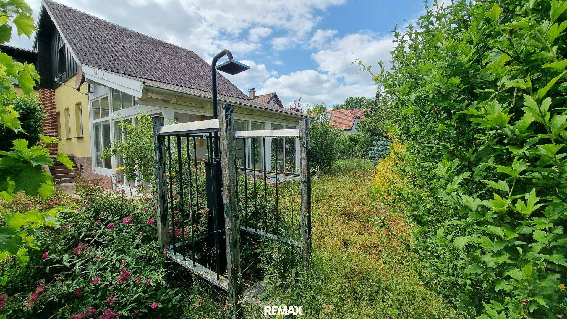 Gartenbereich mit üppiger Vegetation und einer Außendusche.