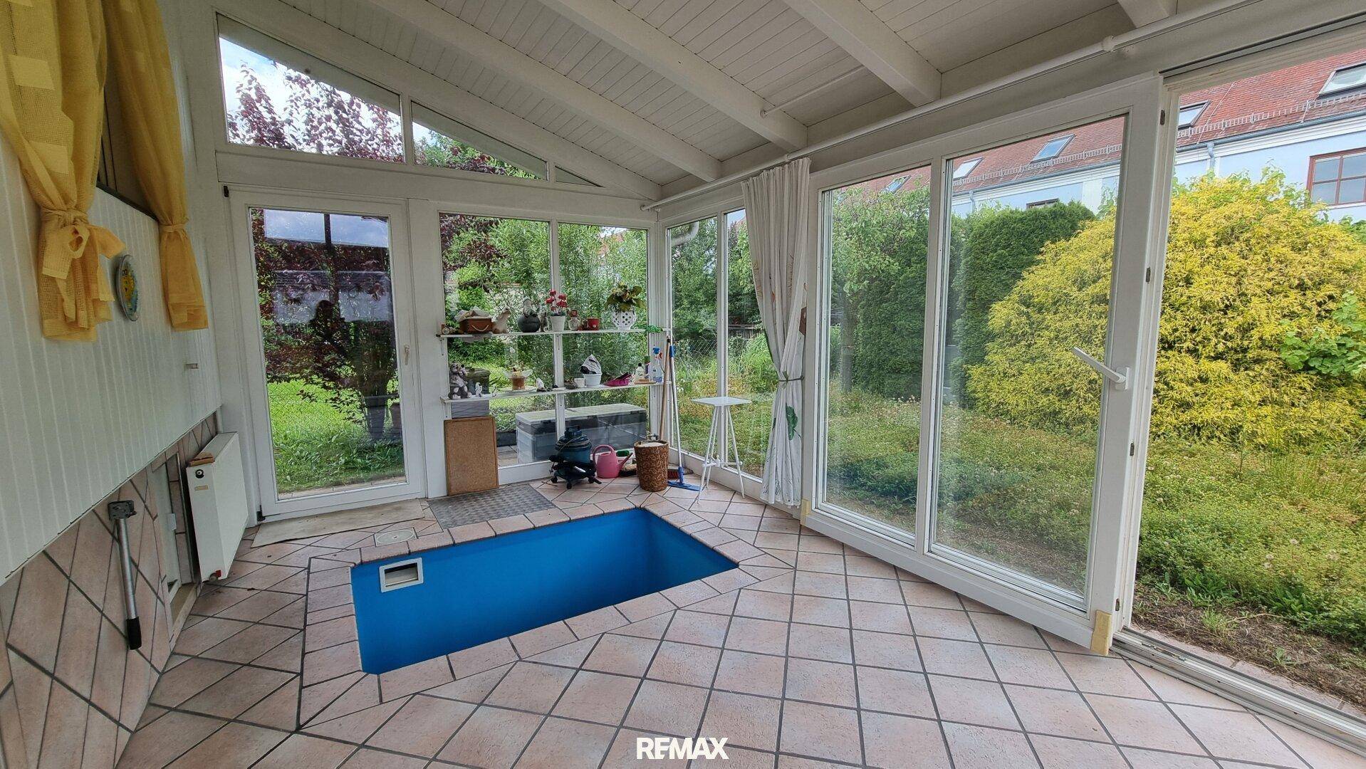 Heller Wintergarten mit kleinem eingelassenem Pool und direktem Zugang zum Garten.