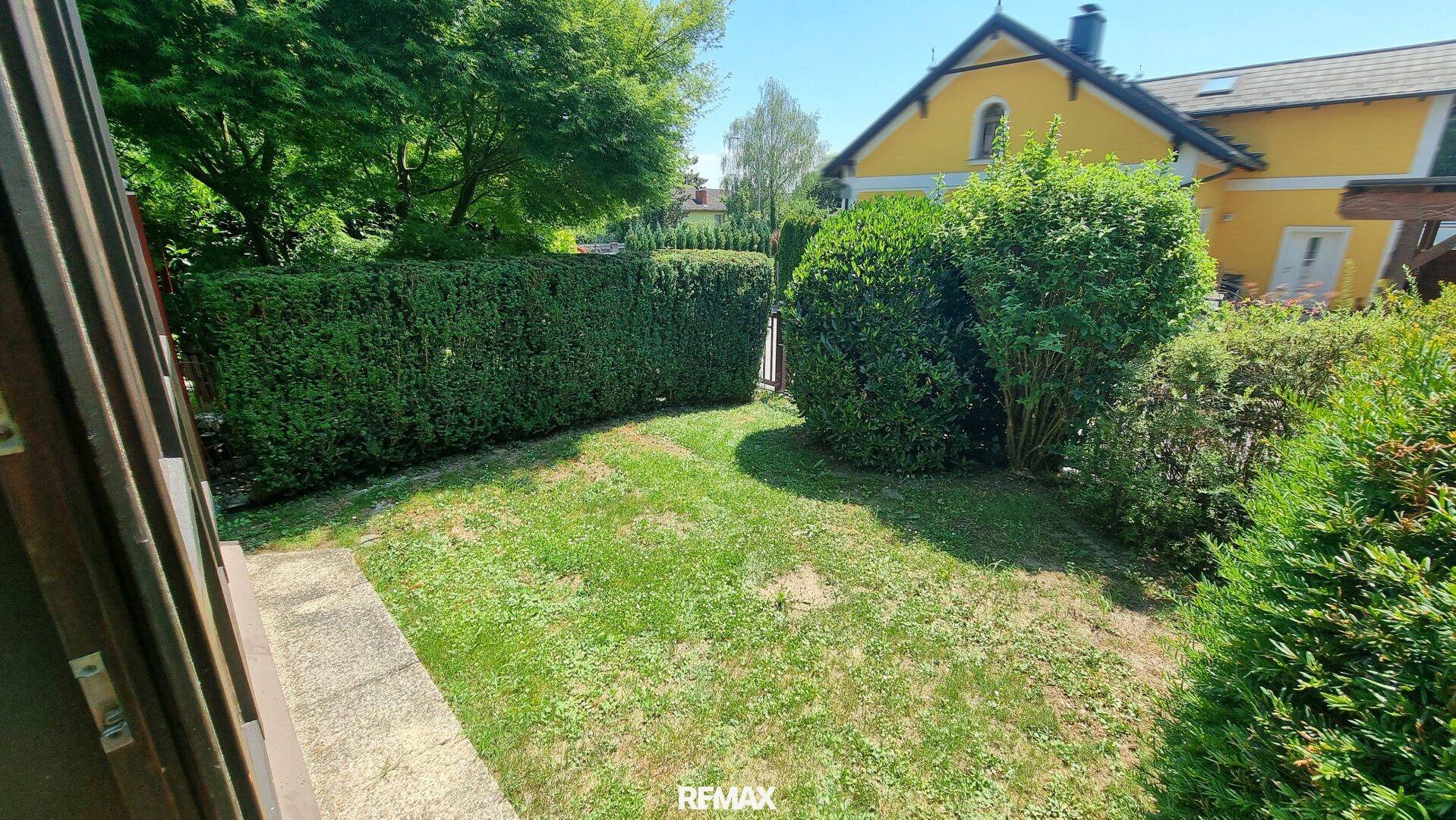 Kleiner, gepflegter Gartenbereich mit grüner Hecke und Rasenfläche, ideal zum Entspannen.