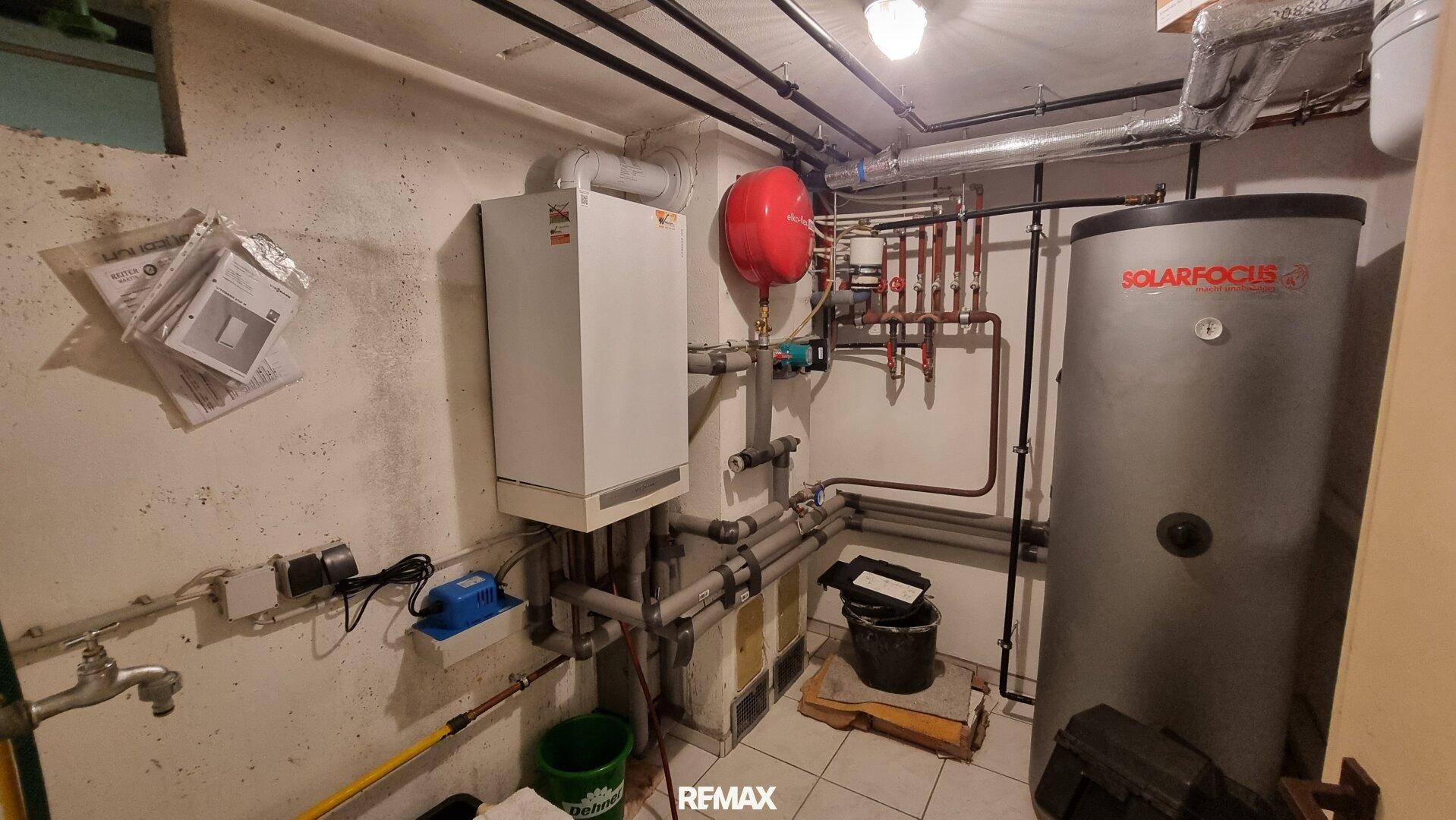 Heizungsraum mit Warmwasserspeicher, sichtbaren Rohren und technischer Ausstattung des Hauses.