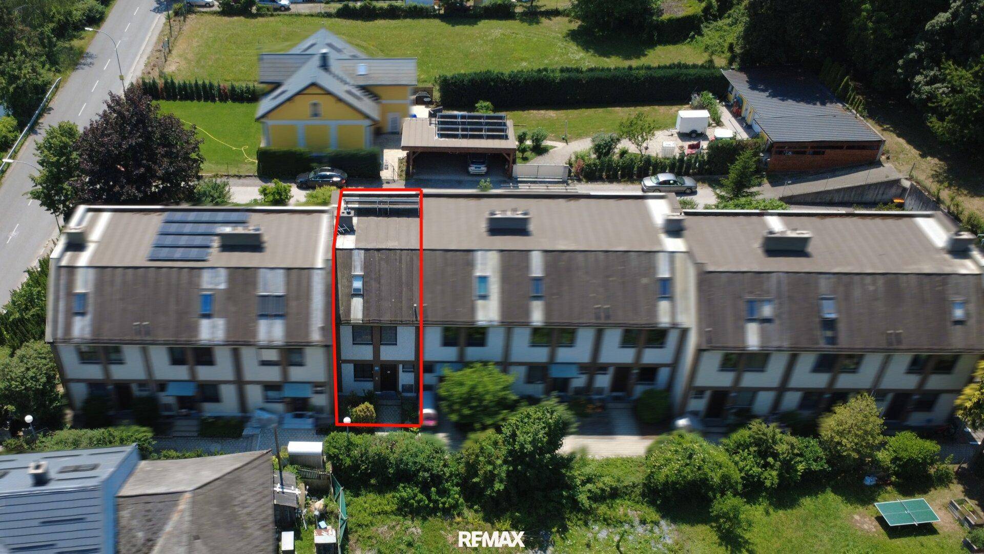 Vogelperspektive einer Reihenhaussiedlung mit viel Grün und dem zum Verkauf stehenden Objekt in Rot umrandet.