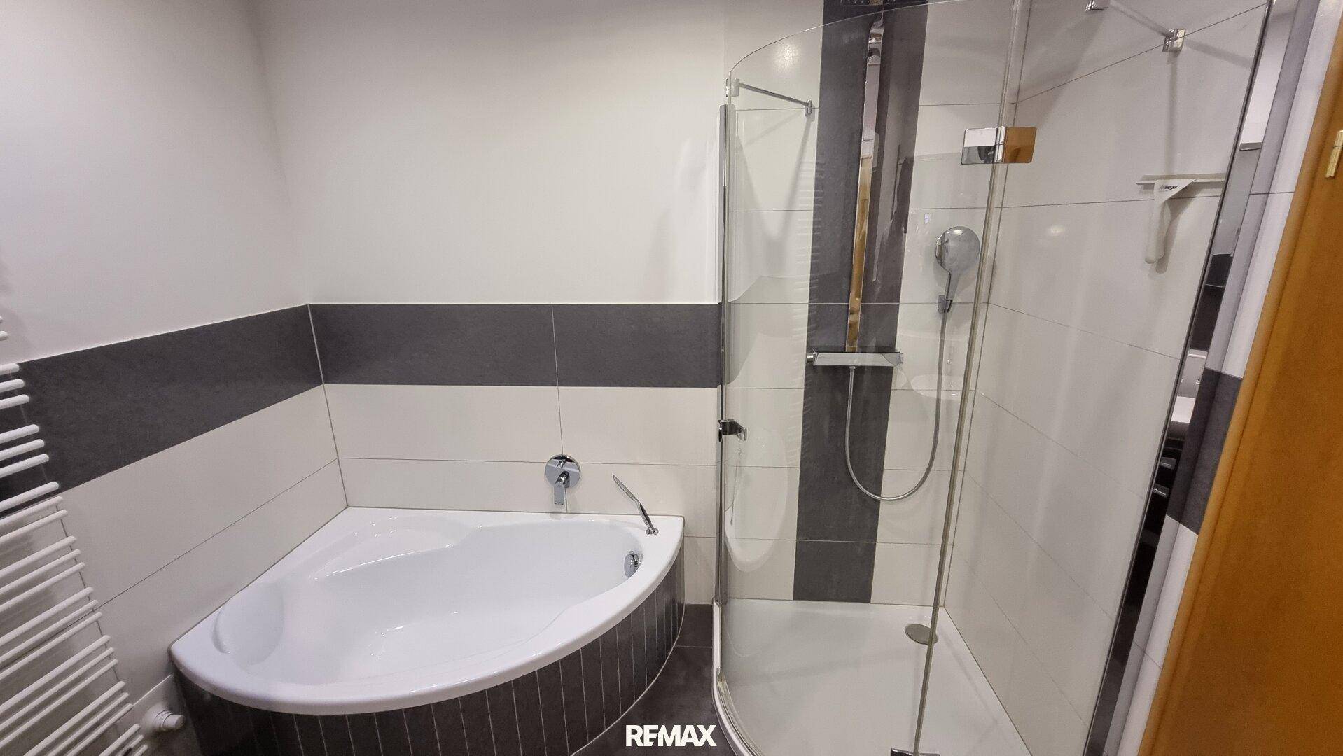 Badezimmer mit Eckbadewanne, Duschkabine und beheiztem Handtuchhalter für zusätzlichen Komfort.