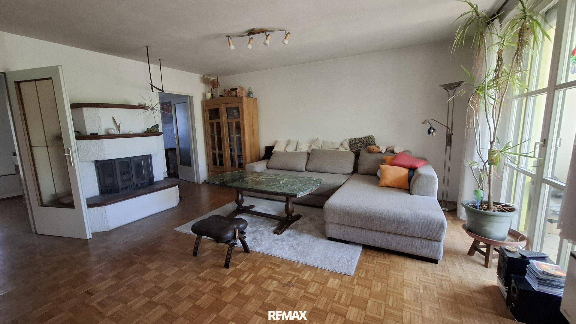 Gemütliches Wohnzimmer mit Ecksofa, Parkettboden und traditionellem Kamin.