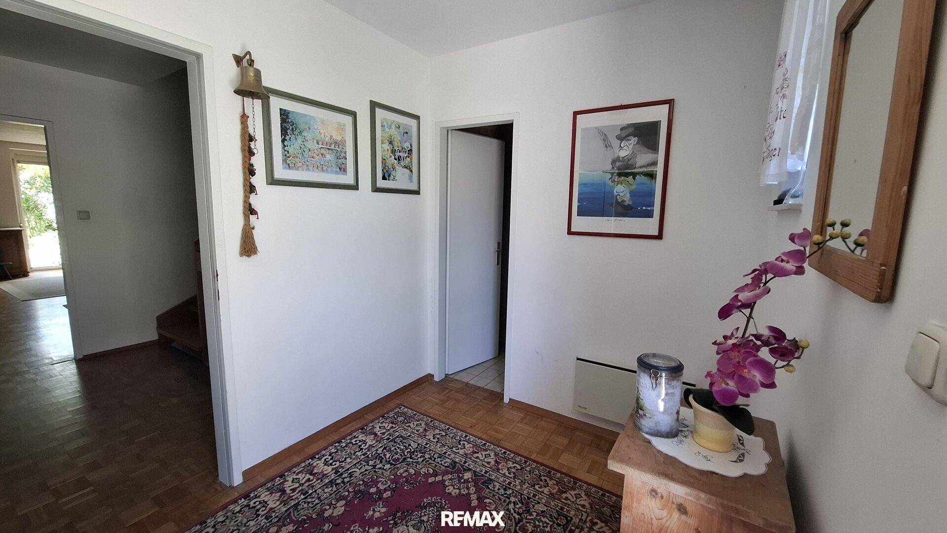 Eingangsbereich mit Parkettboden, Teppich und dekorativen Bildern an der Wand.