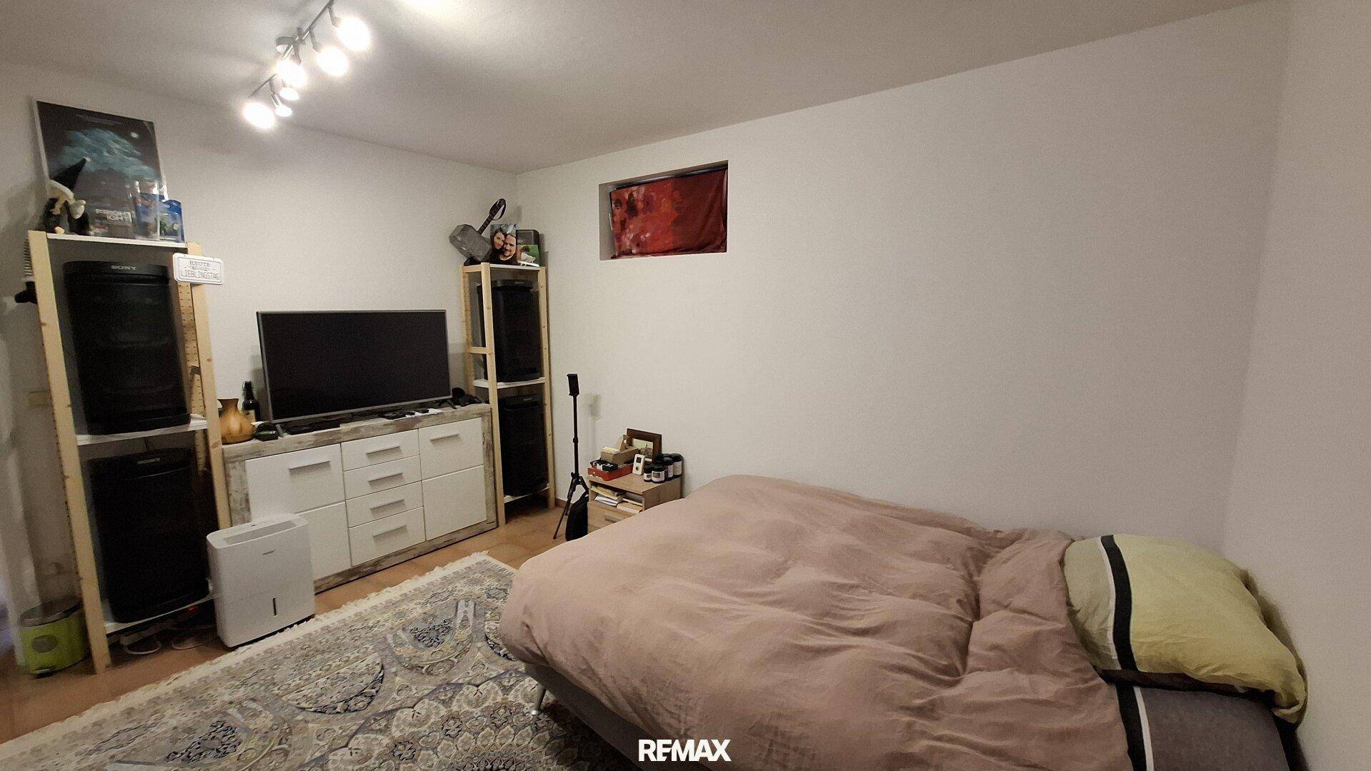 Gemütliches Schlafzimmer im Untergeschoss mit Teppich und Fernseher.