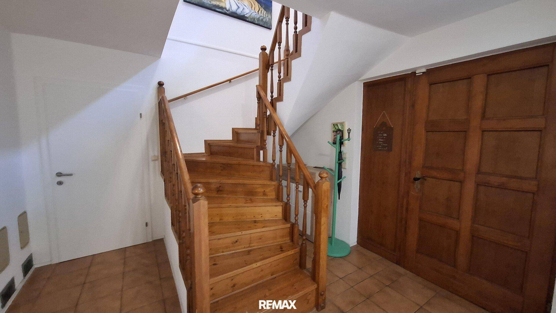 Helles Treppenhaus mit Holztreppe und Geländer, verbindet die Stockwerke des Hauses.