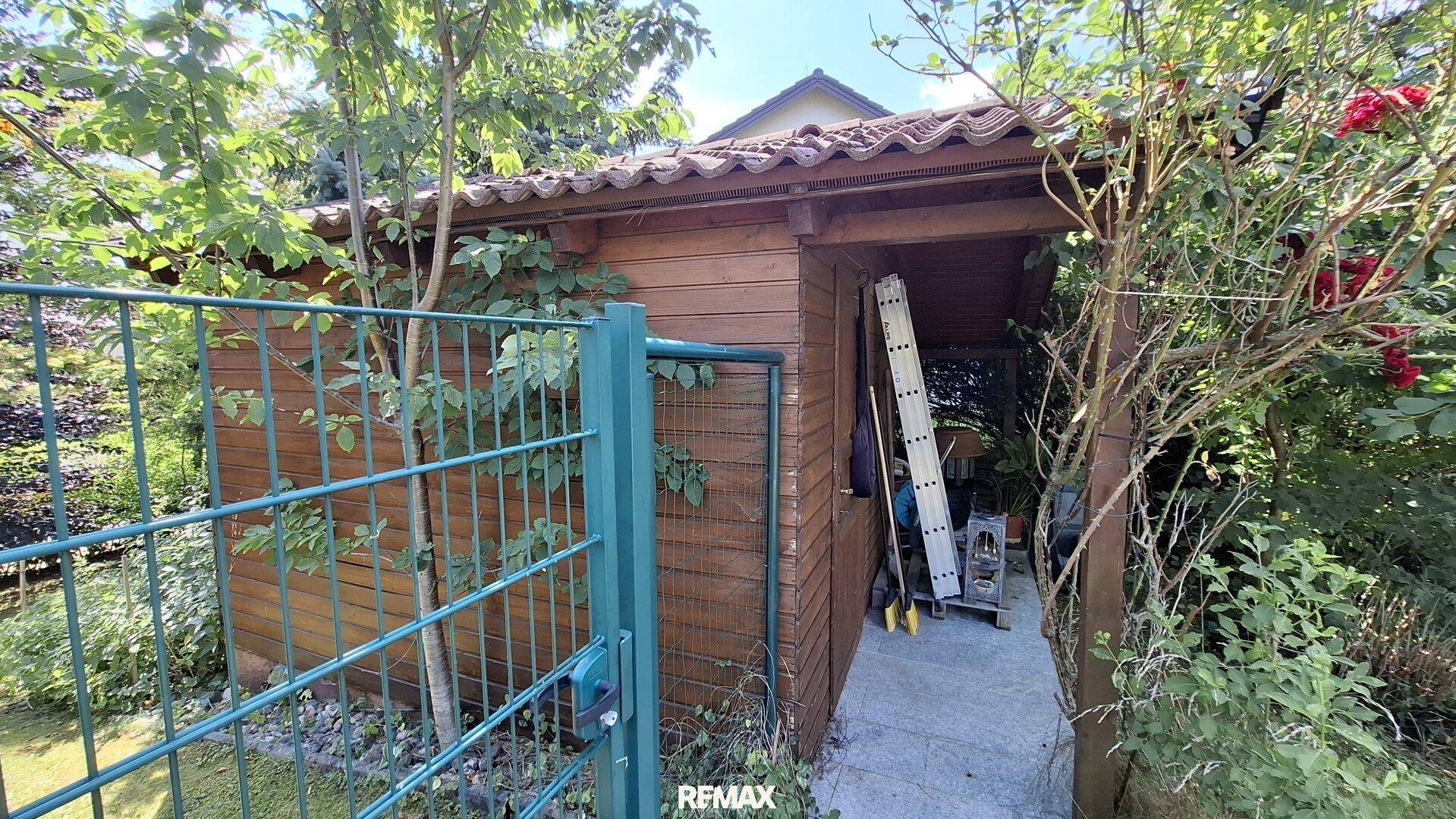 Rustikales Gartenhaus aus Holz, umgeben von üppigem Grün.
