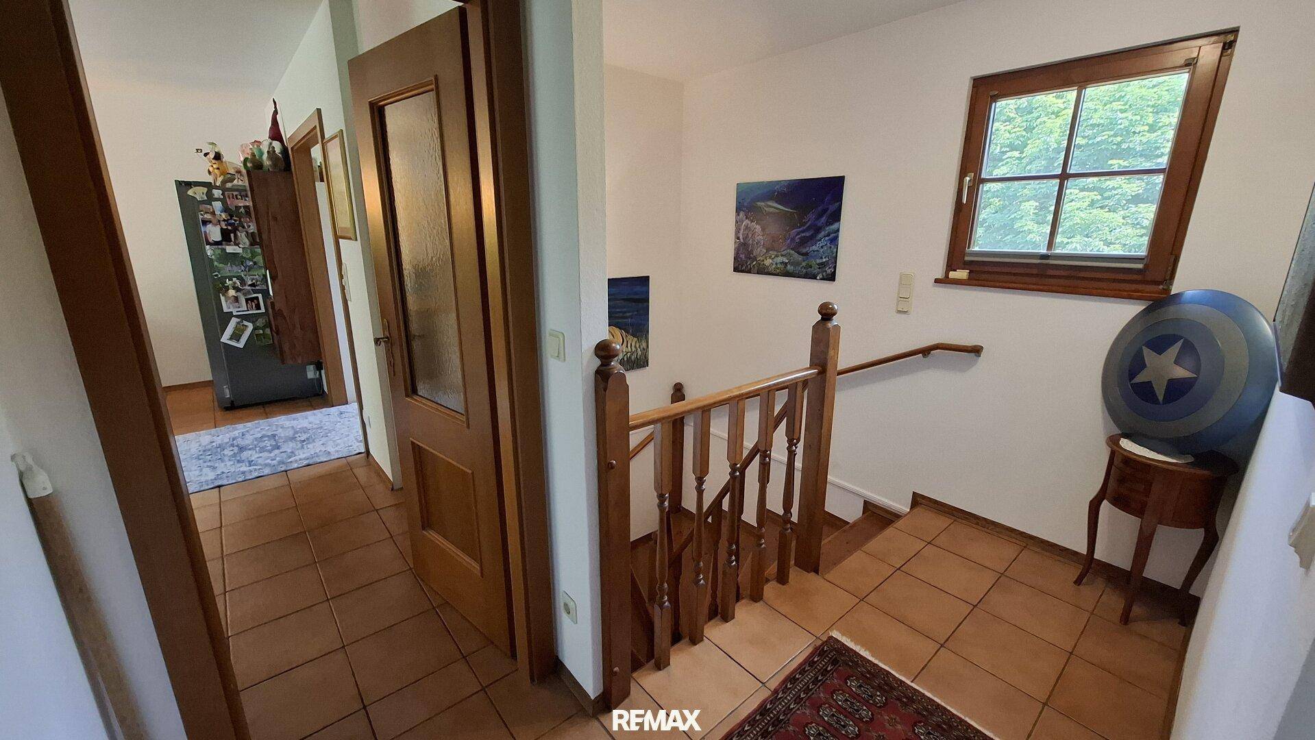 Heller Flur im Obergeschoss mit Holztreppe und Fenster zum Garten.