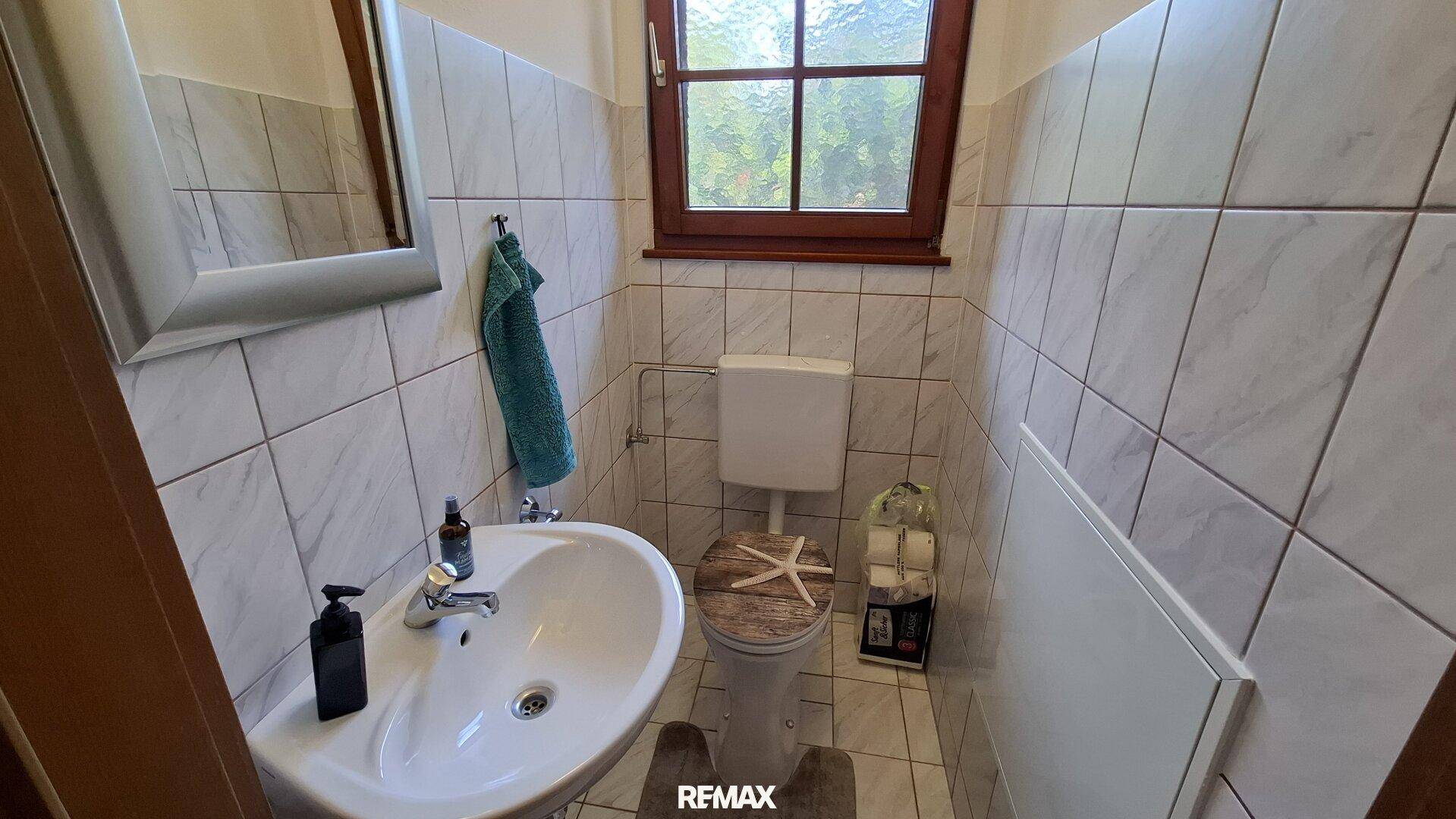 Kleines Gäste-WC mit Fenster, Waschbecken und WC.