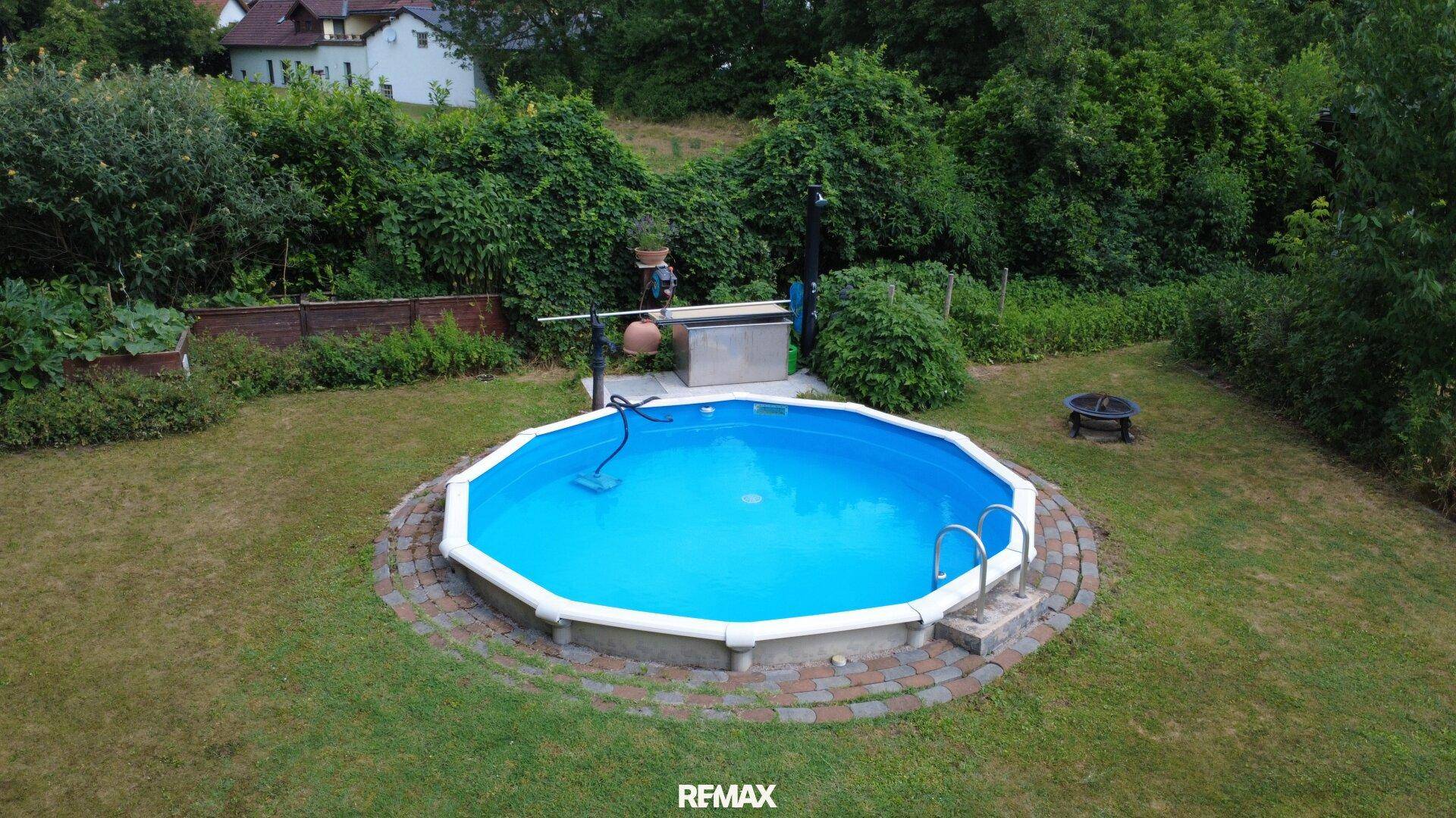 Runder Aufstellpool im Garten, umgeben von einer gepflegten Rasenfläche.