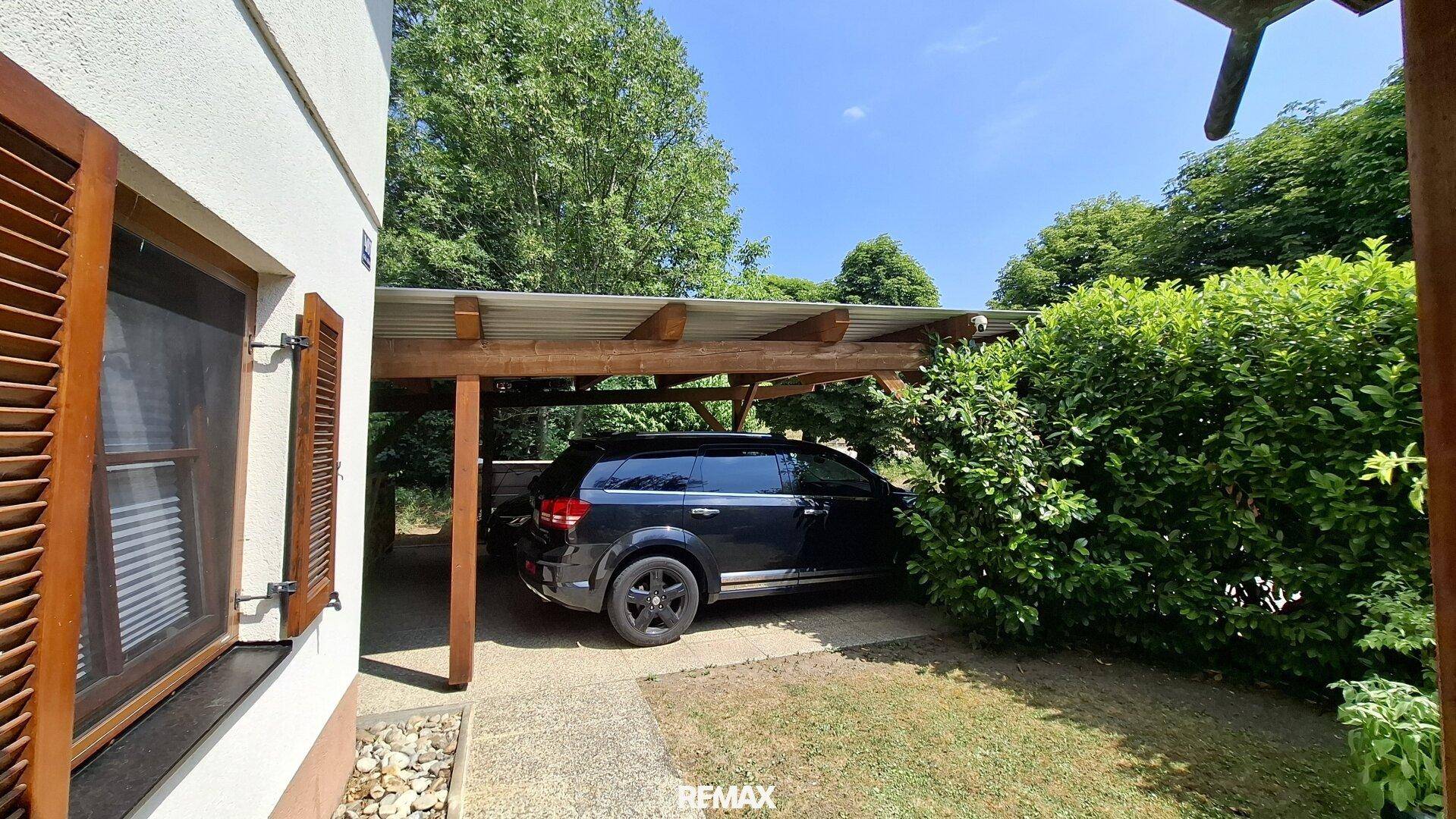 Geräumiger Carport neben dem Haus, bietet Schutz für Fahrzeuge.