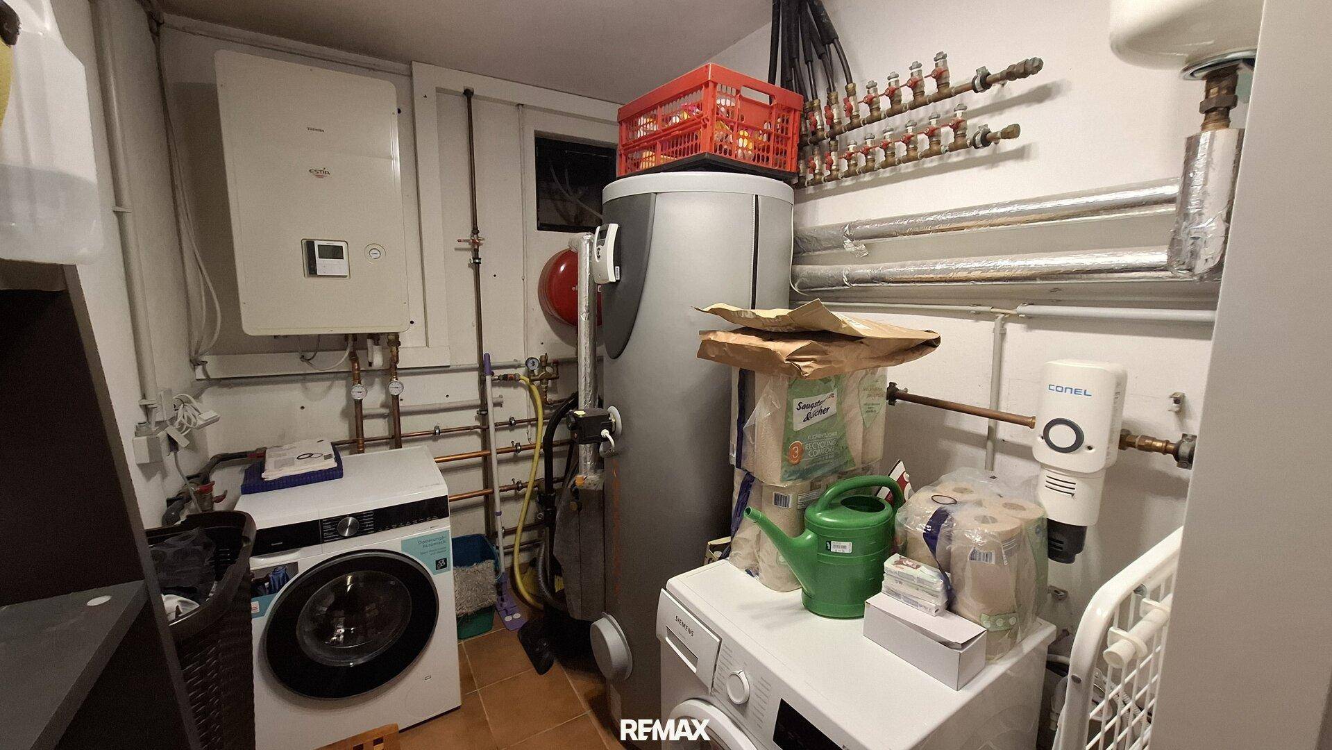 Praktischer Hauswirtschaftsraum mit Waschmaschine, Trockner und Warmwasserboiler.