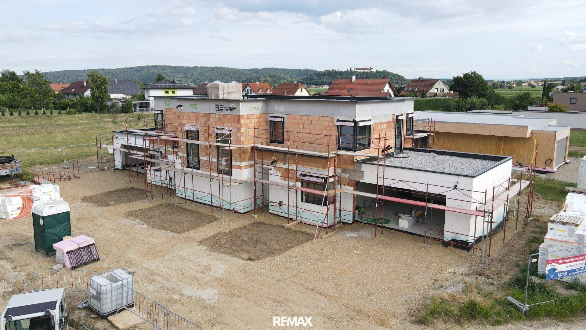 Drohnenaufnahme eines modernen Neubaus im Rohbau mit Flachdach und ländlicher Umgebung.