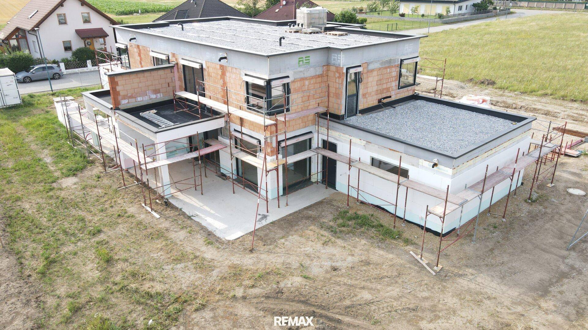 Ansicht des im Bau befindlichen Gebäudes mit moderner Architektur und Flachdach in ländlicher Lage.