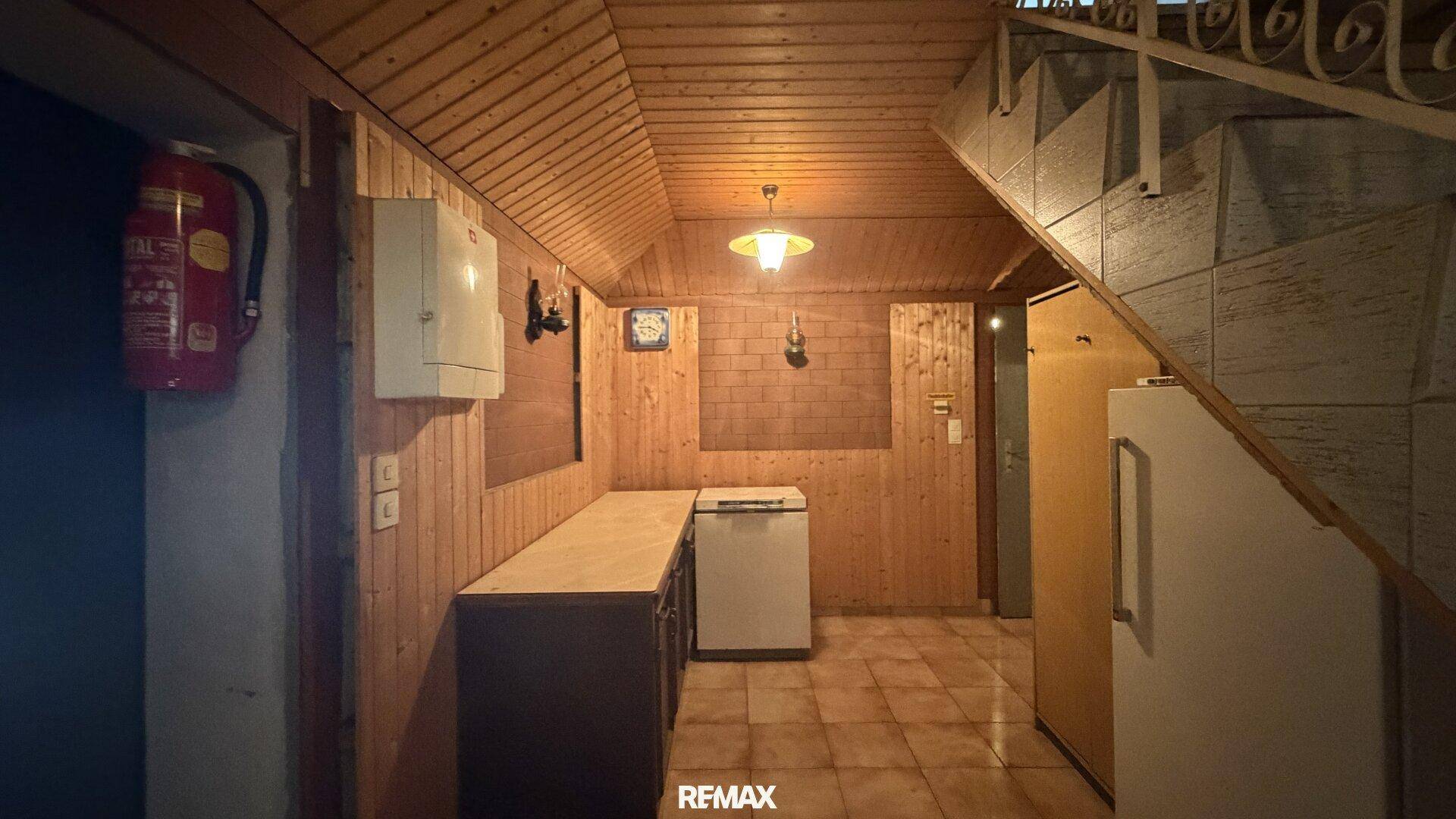 Kellerraum mit Holzvertäfelung, Fliesenboden und einer Treppe, der als Abstellraum dient.
