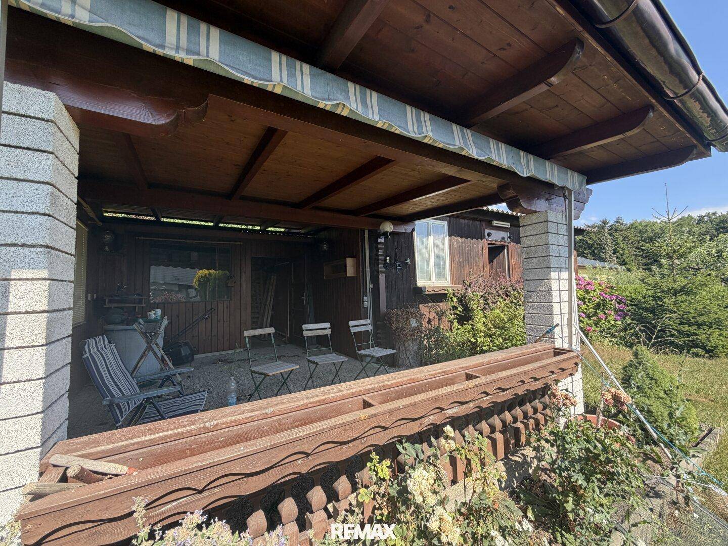 Überdachte Veranda des Gartenhauses mit Sitzgelegenheiten, ideal für entspannte Stunden im Freien.