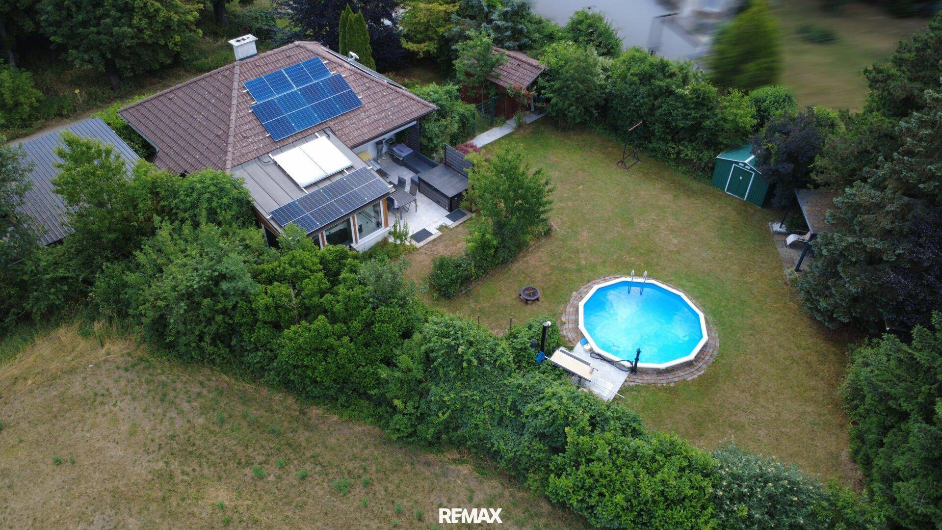 Luftaufnahme des Anwesens mit großem Garten, Pool und Photovoltaikanlage auf dem Dach.