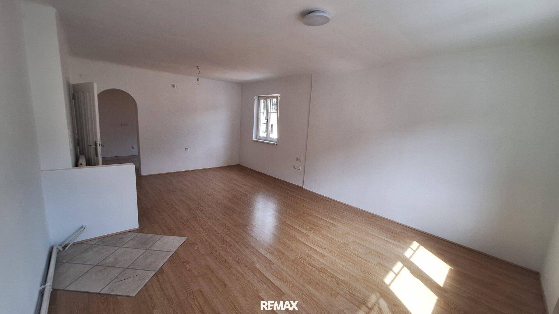 Helles, unfurniertes Zimmer mit Laminatboden und einem Fenster, das viel Tageslicht hereinlässt.