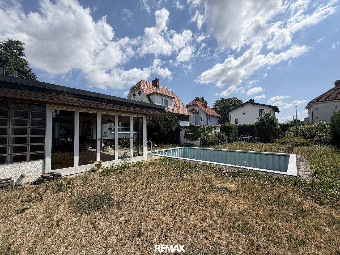 Hinterhof mit Pool und Garten, umgeben von weiteren Häusern und viel Grün.