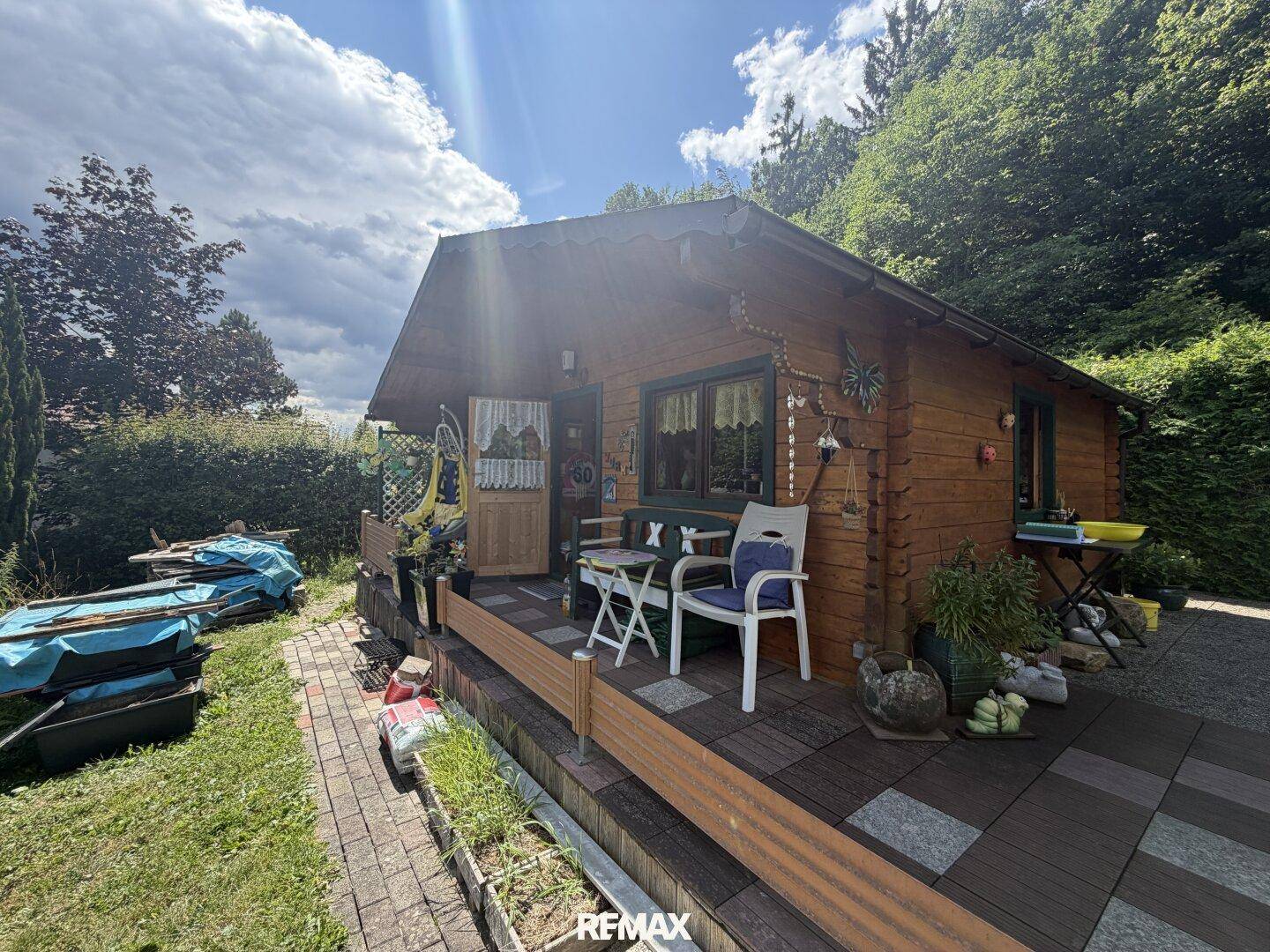 Gemütliche Holzterrasse vor dem Blockhaus mit Sitzgelegenheiten und Gartenblick.