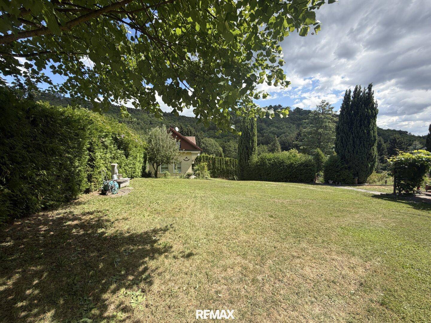 Weitläufige Rasenfläche mit Bäumen und Hecken, umgeben von ländlicher Idylle.
