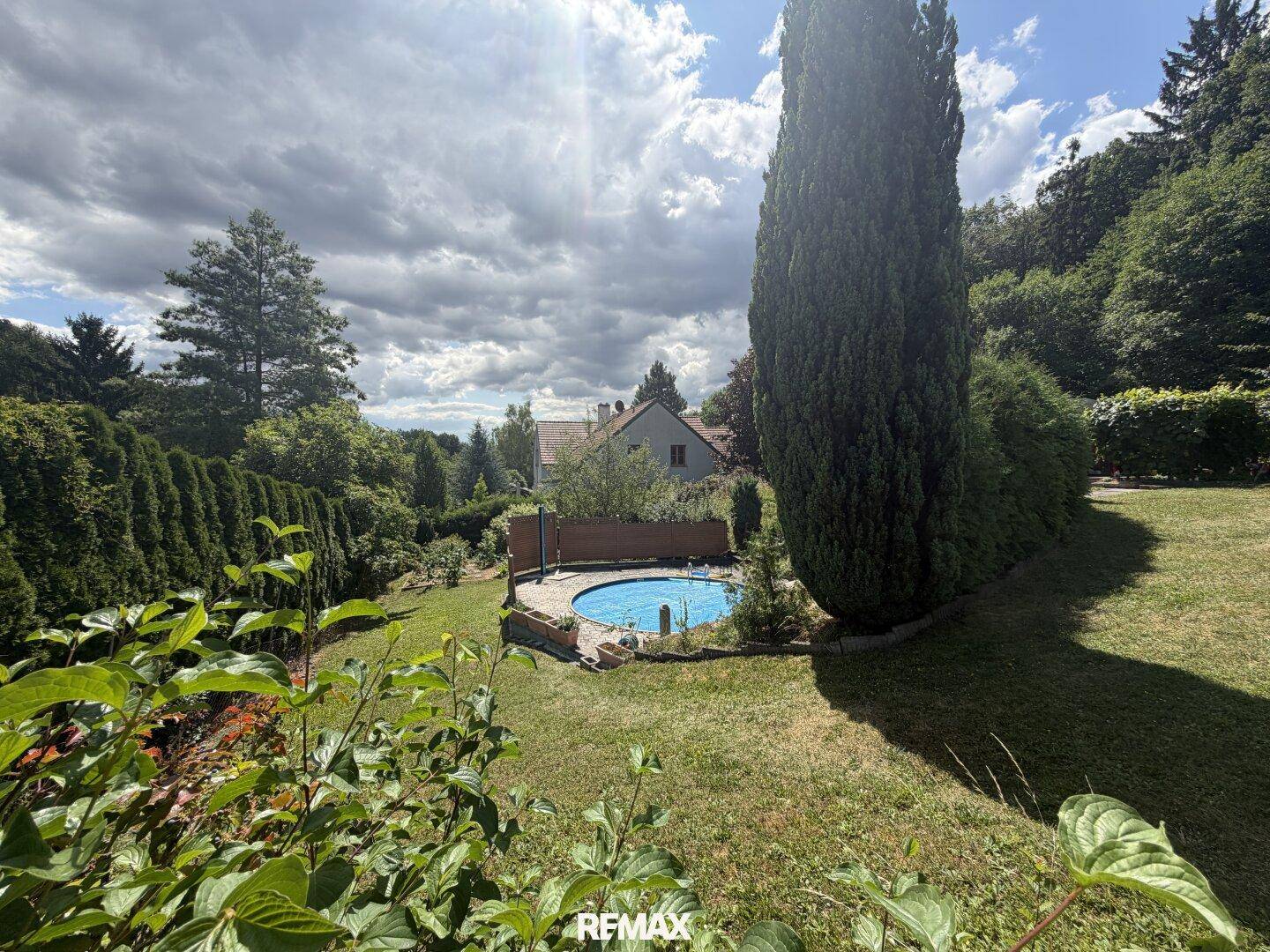 Panoramablick über den Garten mit Pool und einem Haus in der Ferne.