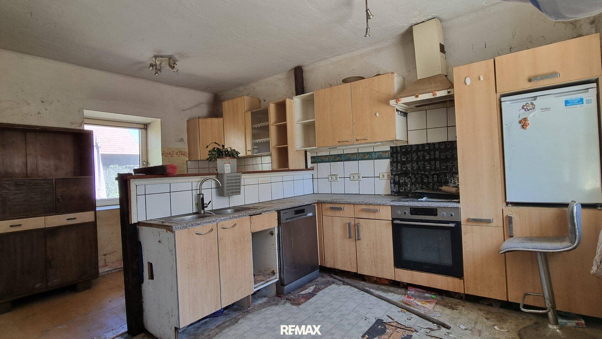 Renovierungsbedürftige Küche mit älteren Holzschränken, Spüle und Einbaugeräten.